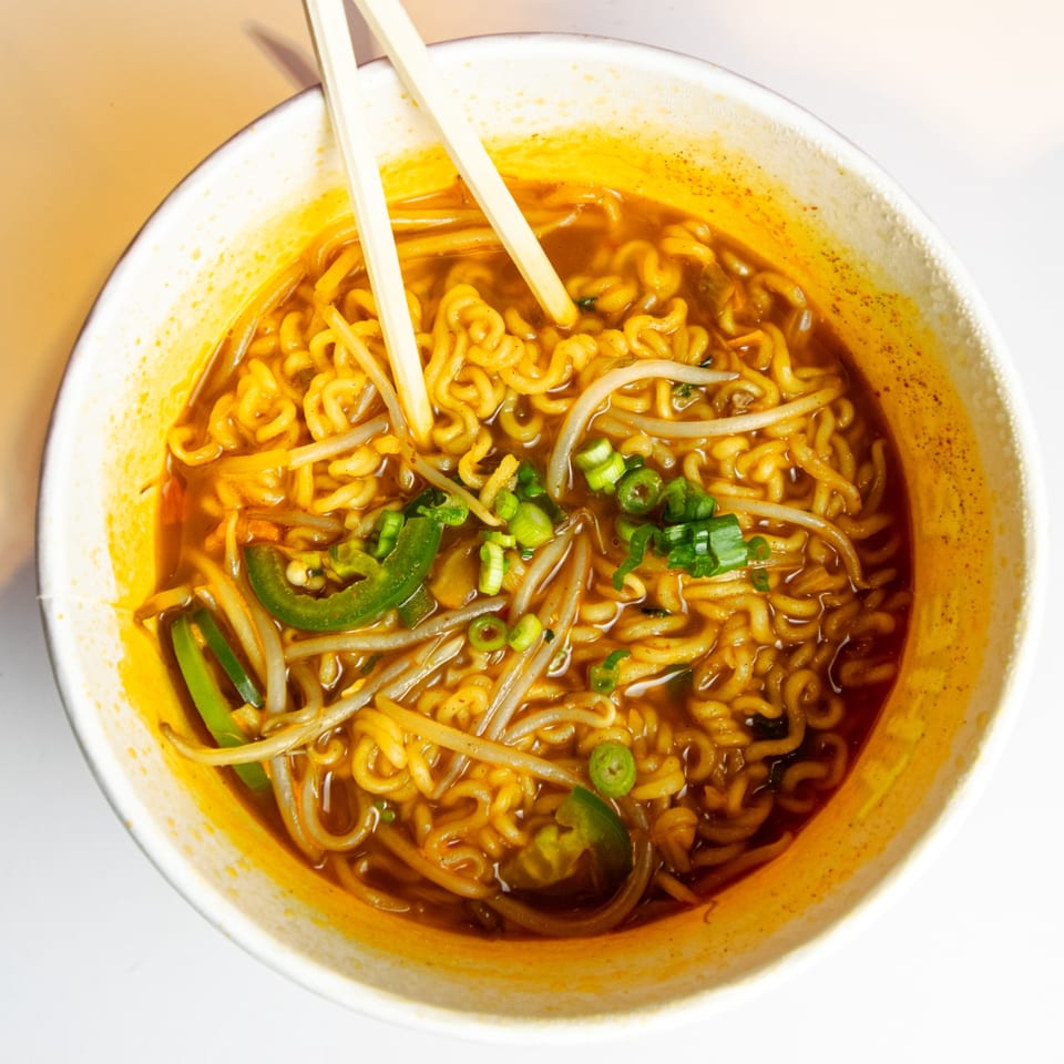 Top-down view of GimMeBap's spicy Korean ramen with noodles, bean sprouts, jalapeños, and green onions.