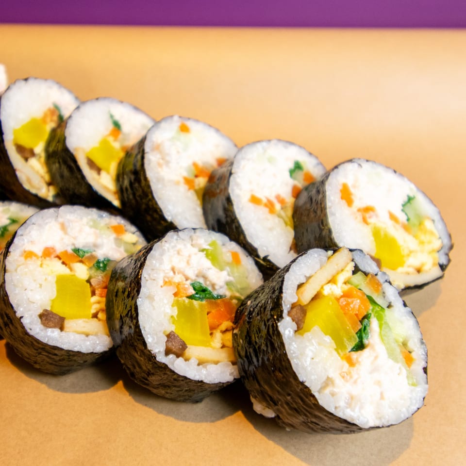 Rows of GimMeBap's Korean gimbap rolls filled with colorful vegetables and rice.